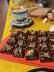 Auf einem Buffettisch steht ein Schokoladenkuchen mit bunten Streuseln verziert. Im Hintergrund sind weitere Kuchen des Buffets zu sehen. 