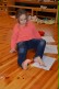 Ein Mädchen sitzt auf dem Boden, mit den Füßen hält sie einen Stift zwischen den Zehen, auf dem Boden liegt ein festgeklebtes Blatt, darauf malt sie.