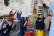 Fünf Kinder üben mit ihren Instrumenten im Workshop Drum Kids. Vor einem Kind steht eine rote Trommel, vor einem anderen eine gelbe Trommel. Alle Kinder halten die Sticks gekreuzt über Kopf.