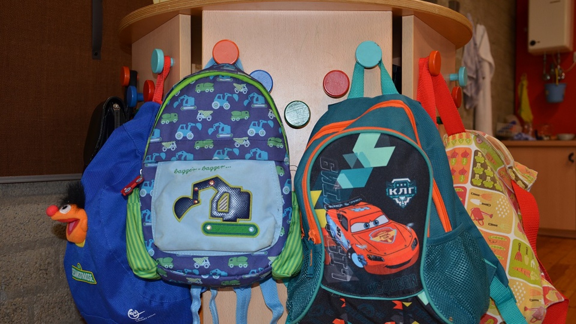 Bunte Kinderrucksäcke Rucksäcke hängen an einer bunten Garderobe.